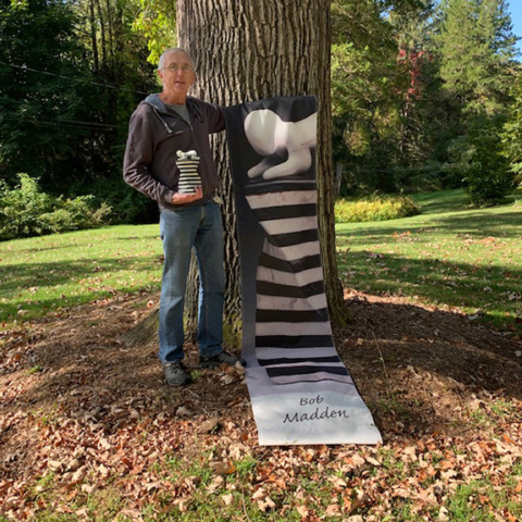 Bob Madden holding black and white sculpture that was reproduced on banner
