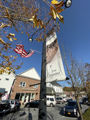 Ann Heywood Banner of earth tone pottery bowl hanging on village street