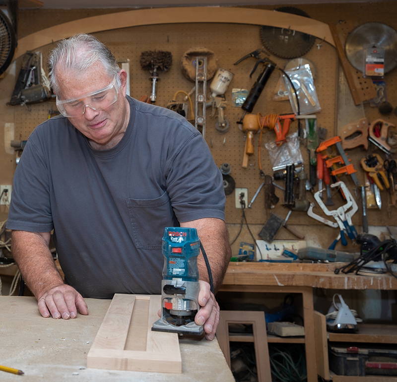 wood artist wearing protective lenses tools hanging on wall in background