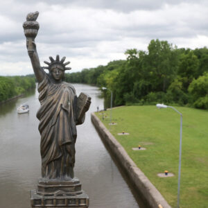 replica Statue of Liberty stands tall over background of Erie Canal