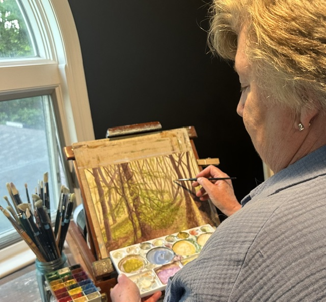 side view of woman with blond hair working on a painting