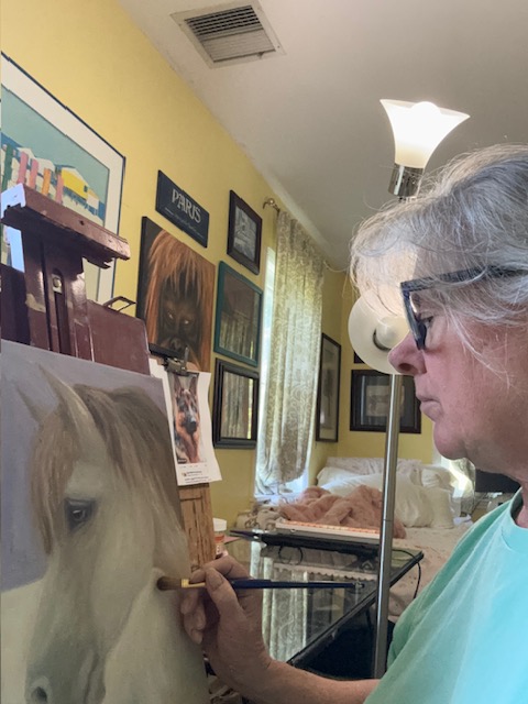 close up of artist in profile working on a painting of a horse