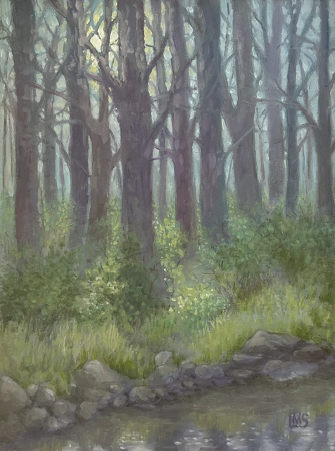 The moon peeking thru the trees and illuminating the green vegetation at the edge of a stream in the woods