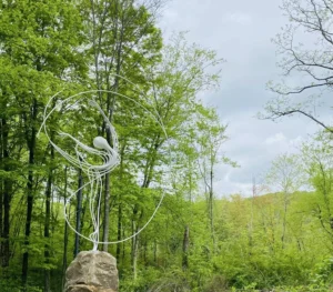15-foot stainless steel sculpture, "Dancer," utilizes minimalist, rhythmic lines to freeze a weightless, spinning motion within the quiet forest.