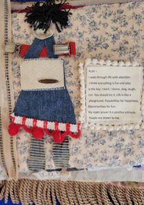 mixed media one page of a book. Blurb about play with a fun character in fabric collage